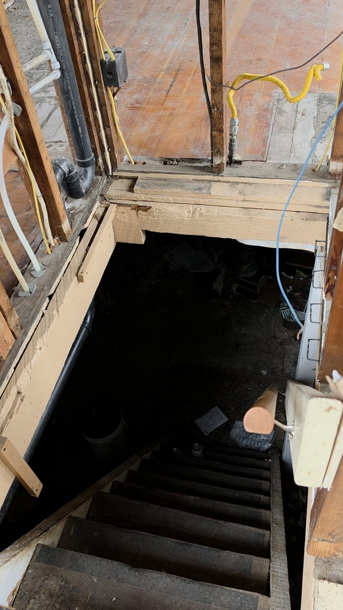 Opening in the floor framing down to the basement stairs